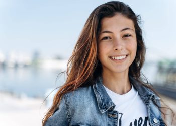 Attractive girl posing against the backdrop of the city. Cute girl - a teenager smiling, looking at the camera, close-up view.